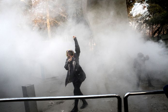 Een studente bedekt zich tegen het traangas om haar heen.