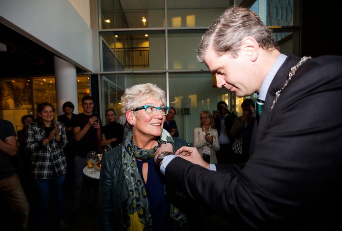 Burgemeester Wouter Kolff speldt het lintje op bij Sjarlot Kooi.