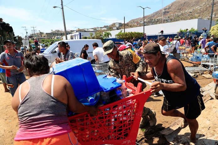 Met boodschappenwagens volgeladen met water en andere eerste levensbehoeften verlaten mensen een supermarkt in de door de orkaan Otis getroffen Mexicaanse stad Acapulco.