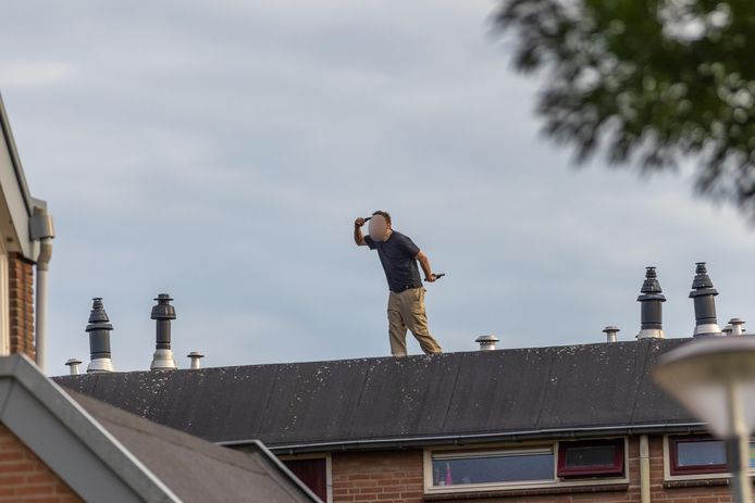 Een verwarde man staat met twee vuurwapens op het dak van een woning in Huissen.