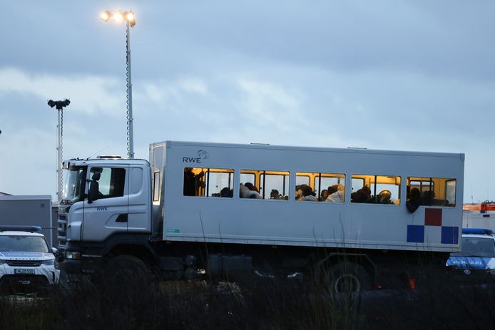 Arrestanten worden door de politie bewaakt in een geïmproviseerde gevangenenbus. (12/01/23)