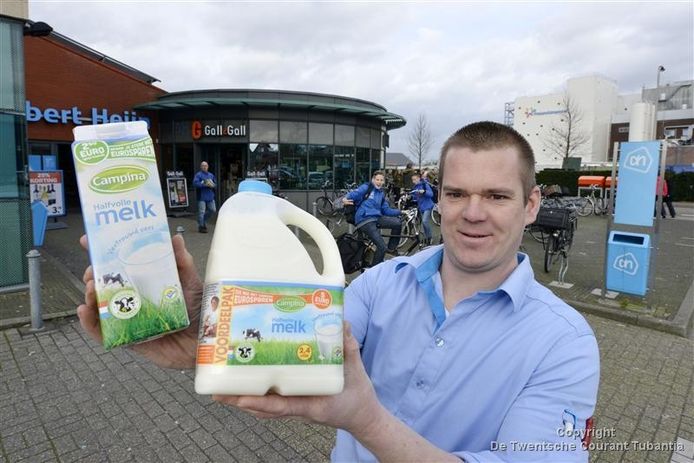 Teamleider Ard Timmerije van Albert Heijn met pakken Campinamelk die inmiddels weer in de schappen van de supermarkt staan. Op de achtergrond de FrieslandCampina fabriek.