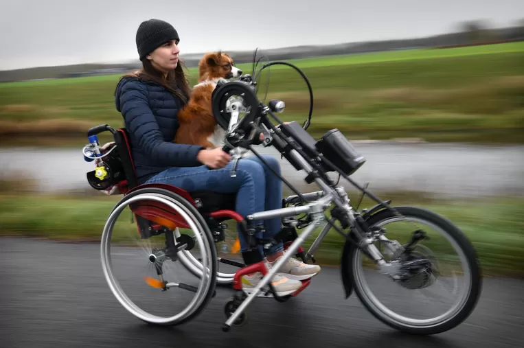 Celine Hermans en haar hondje op de handbike.