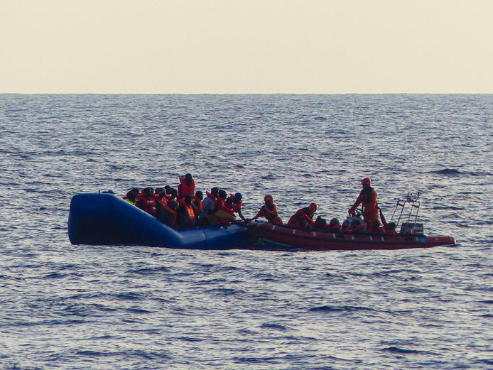 De groep migranten op een rubberboot in de zee voor Libië.