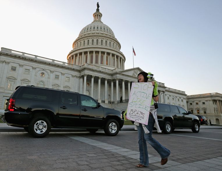 Een vrouw demonstreert maandag voor het Capitool in Washington tegen het onvermogen van de Amerikaanse politici: 'Hou op je te gedragen als verwende ettertjes', staat op haar bord. Beeld afp
