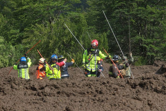 Reddingswerkers zoeken naar overlevenden in de modder na de aardverschuiving in  Villa Santa Lucía.