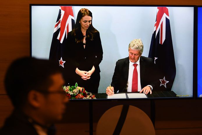 De premier van Nieuw-Zeeland, Jacinda Ardern, ziet hoe haar minister van Handel, Damien O'Connor, zijn handtekening zet.