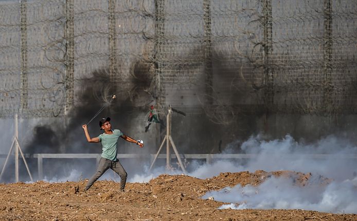 Een Palestijn gooit met stenen naar de Israëlische troepen.