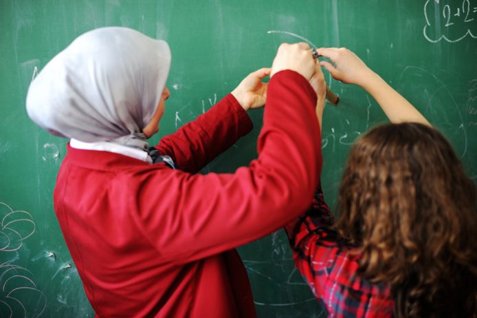 Arabic Muslim teacher showing school girls on the classroom board