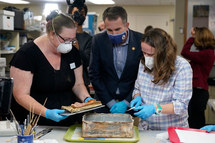 De gouverneur van Virginia, Ralph Northam, kijkt toe hoe de tijdscapsule geopend wordt door conservatoren Kate Ridgway (links) en Sue Donovon op de University of Virginia.