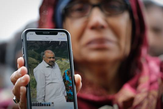 Een vrouw toont een foto van haar vermiste echtgenoot.