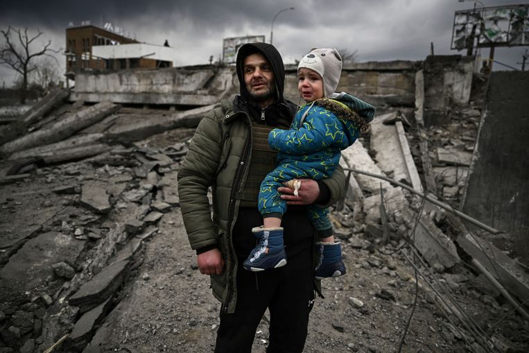 Man met kind ontvlucht Irpin, een stad ten westen van Kyiv, 7maart, 2022.  Beeld AFP