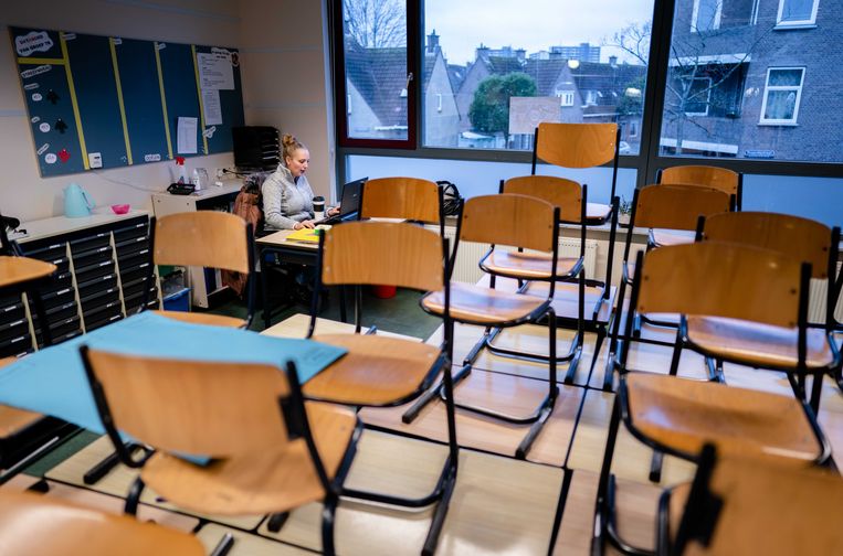 Juf Jessie van Groep 7 heeft in een leeg klaslokaal van basisschool Jeroen in Den Haag online contact met leerlingen.  Beeld ANP