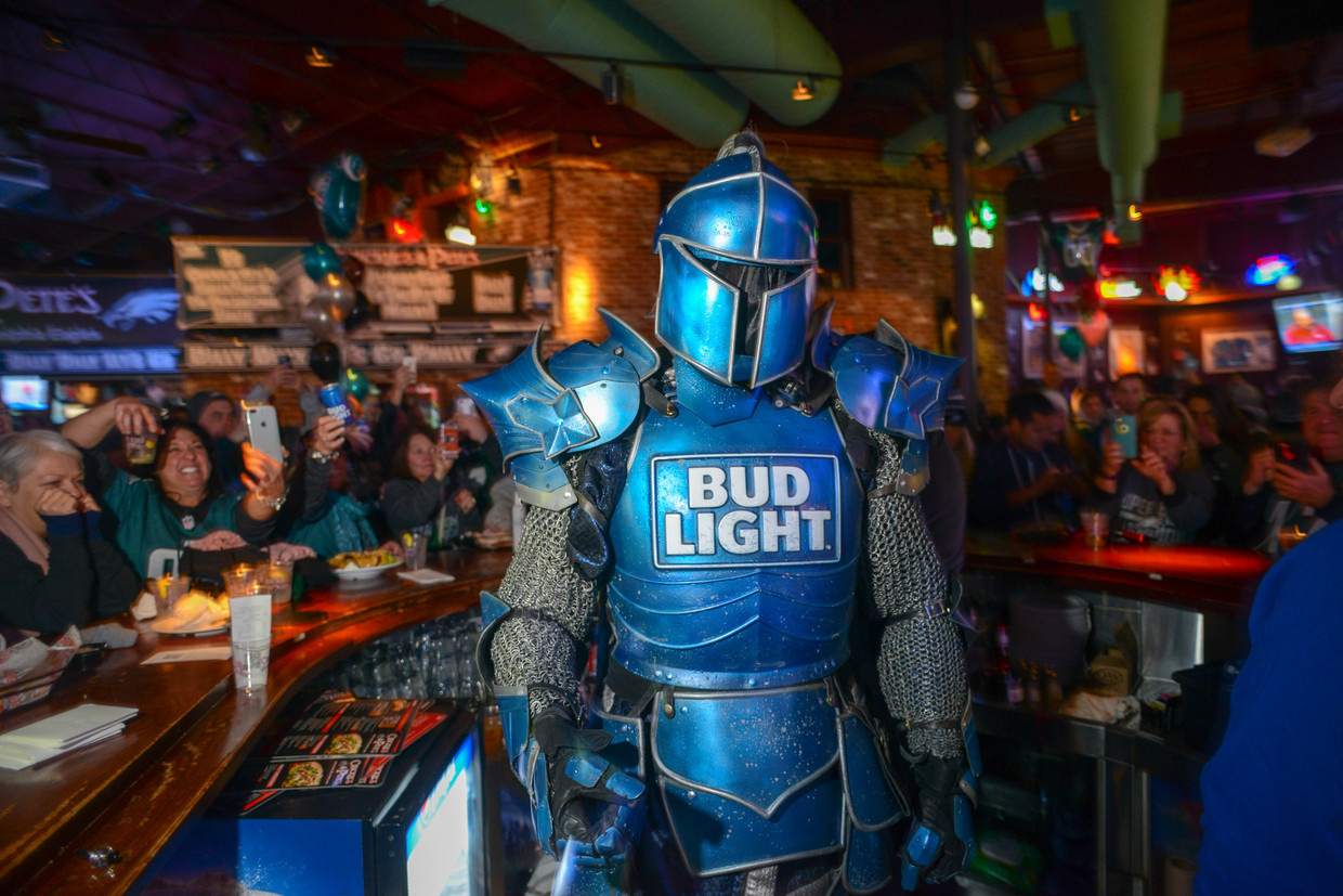 Een man in harnas, bekend van Bud Light-reclames op de Amerikaanse televisie, deelt handtekeningen uit in een bar in Philadelphia. Beeld Getty Images
