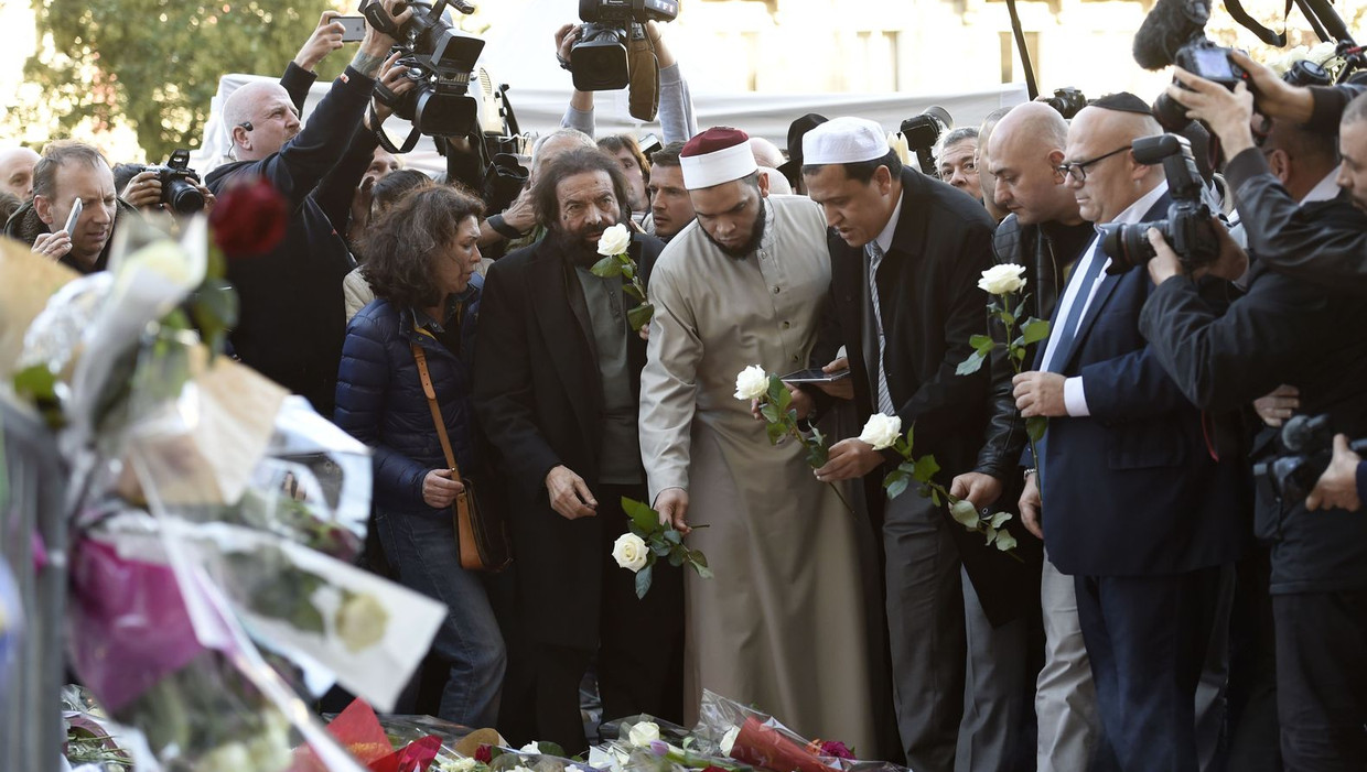 De Franse auteur Marek Halter (4e van links), Imam van de Drancy Moskee, Hassene Chalghoumi (6e van links), en overige leden van joodse en moslim gemeenschappen leggen een bloem bij een gemaakt herdenkingsmonument nabij de Bataclan concertzaal. Beeld afp