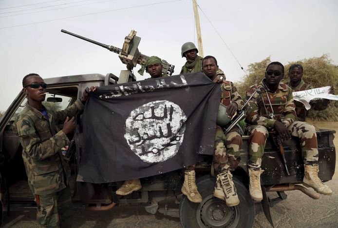 Nigeriaanse soldaten houden een in beslag genomen vlag van Boko Haram vast.