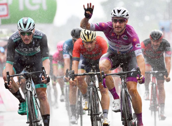 Viviani steekt vier vingers de lucht in na zijn vierde sprintzege. Links: Sam Bennett baalt.