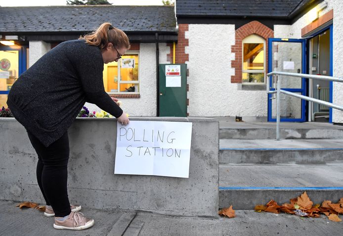 Een Ierse vrouw brengt in Dublin een provisorische aanwijzer voor een stemlokaal aan voor het referendum over godslastering en de presidentsverkiezing.