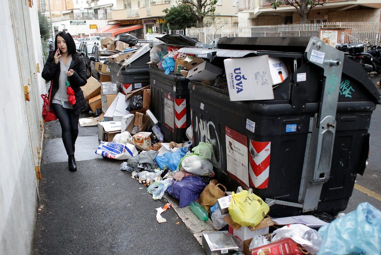 Een vrouw loopt langs vuilnisbakken in Rome, Italië. Beeld Reuters