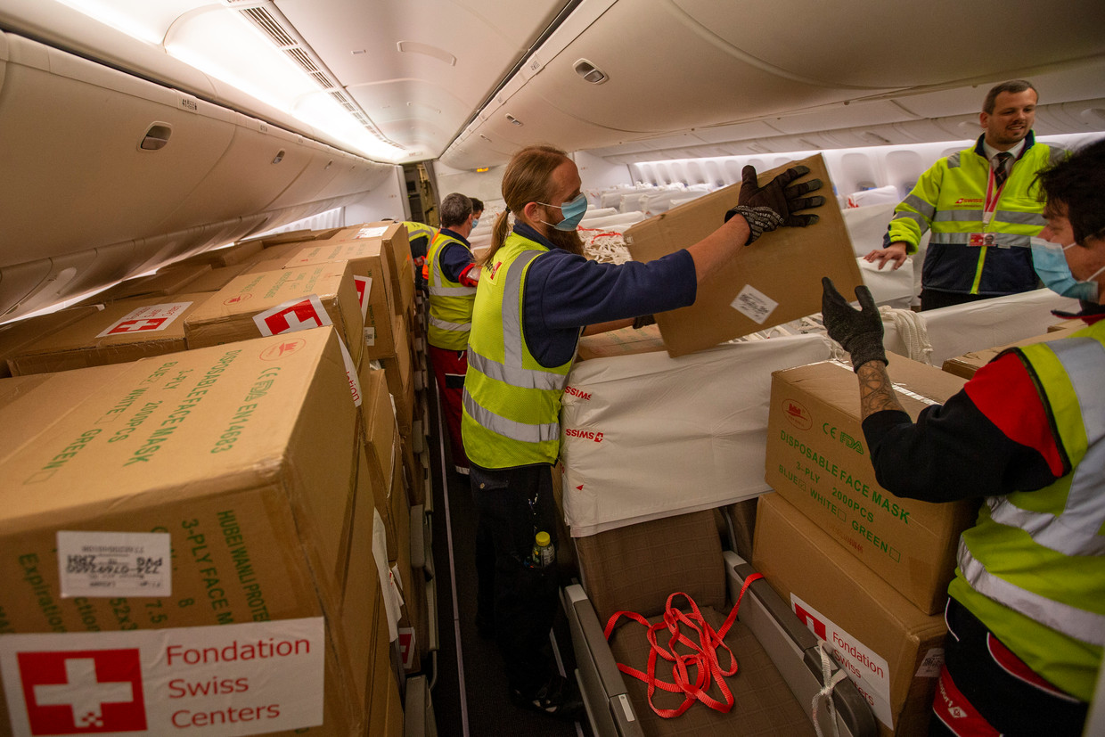 Dozen met beschermingsmiddelen worden uit een passagiersvliegtuig geladen in Genève. Beeld Salvatore Di Nolfi / AP
