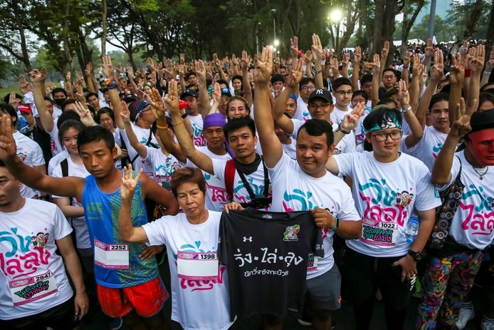 Joggers steken drie vingers op bij de start van de protestjog ‘Run Against Dictatorship’ in een park in Bangkok.
