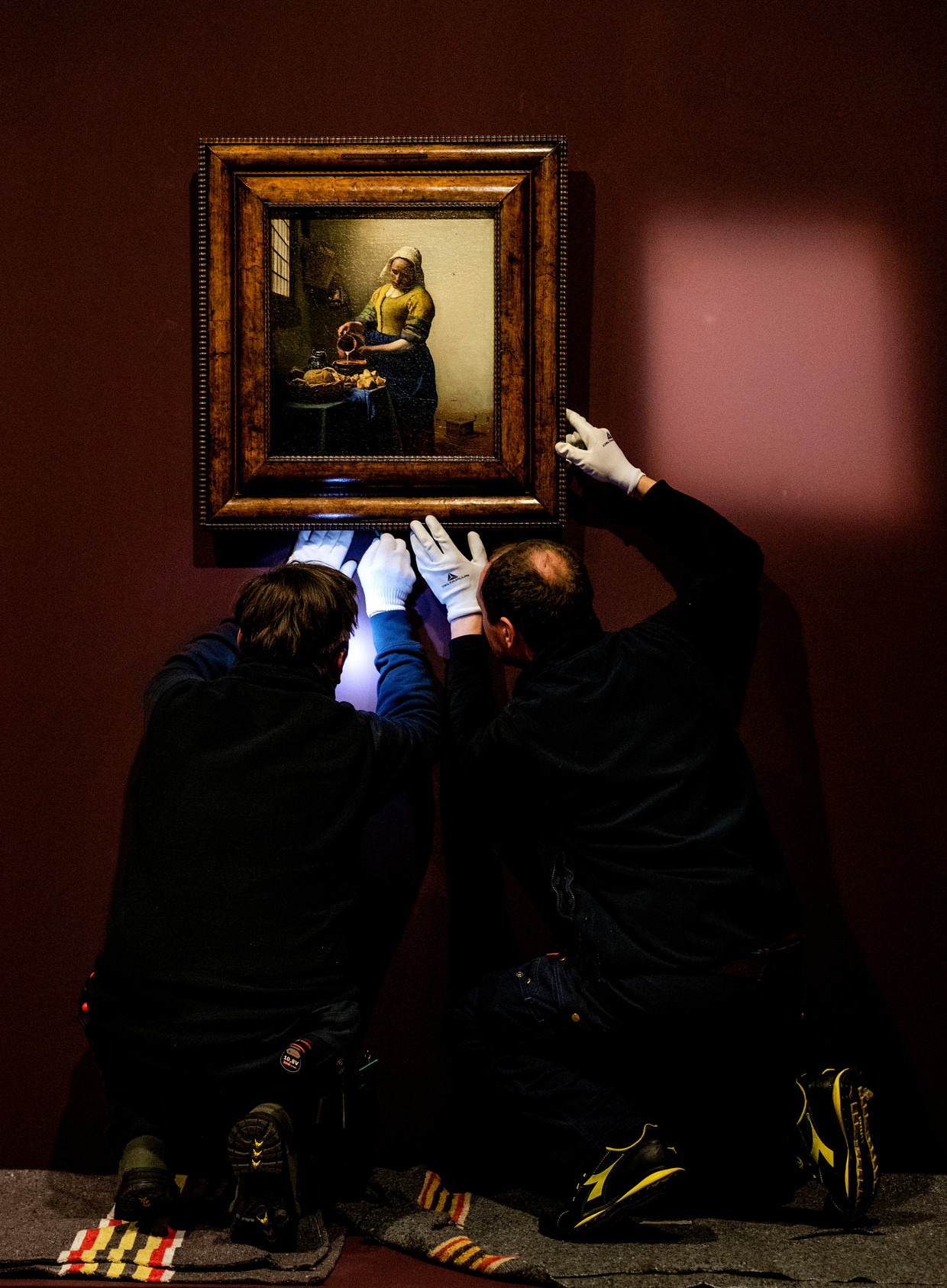Medewerkers van Musee du Louvre hangen het melkmeisje van Johannes Vermeer op. Beeld ANP