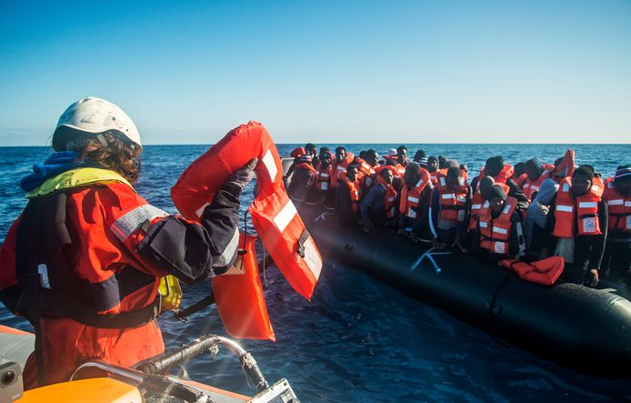 Medewerkers van Seawatch helpen migranten aan boord van het schip