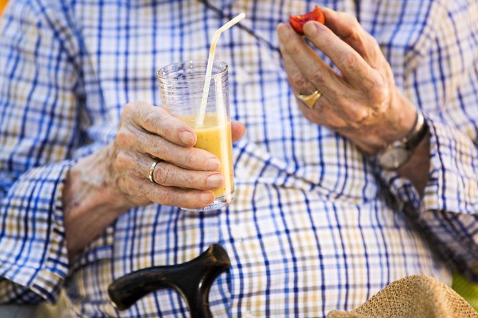 Een bewoner van een verzorgingshuis drinkt ter verkoeling een smoothie. Wegens het warme weer is het Nationaal Hitteplan ingegaan