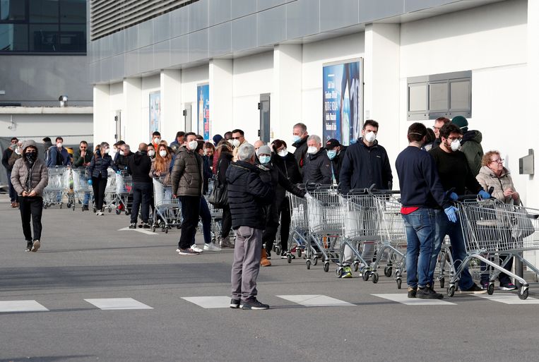 Mensen vormen een rij buiten een supermarkt in Casalpusterlengo, dat in verband met de uitbraak is afgesloten door de Italiaanse overheid. Beeld REUTERS