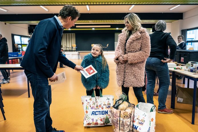 Hoofdredacteur Joris Gerritsen deelt gratis abonnementen uit bij de voedselbank in Wijkcentrum Hatert.  Moeder Linda en dochter Luna Xhofleer zijn er blij mee.