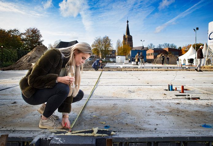 Toekomstige bewoners Demi en Robert meten bij de feestelijke start van bouwproject Achter t Lint de oppervlakte van hun woning op. Op de achtergrond de kerktoren van Leende.