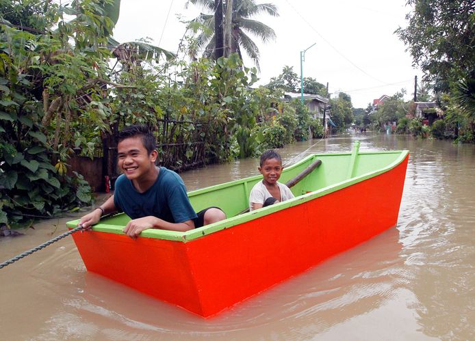 Kinderen gebruiken een boot in Bulan in de Filipijnen. De regio werd zwaar getroffen door de tropsische depressie Usman.
