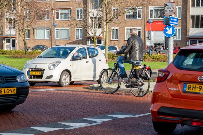 Een fietser en de donkere auto links wachten op het opstelpunt in het midden van de President Rooseveltlaan tot ze kunnen oversteken naar de respectievelijk noordelijke en zuidelijke kant van de Bloemenlaan op een doorsnee maandagmiddag.