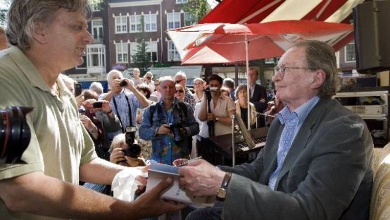 Schrijver Remco Campert (R) signeert een boek voor een fan in Amsterdam. Ter gelegenheid van zijn tachtigste verjaardag werd Campert gehuldigd. Tientallen Nederlandse schrijvers en dichters brachten een ode aan de schrijver Remco Campert. ( ANP) Beeld 