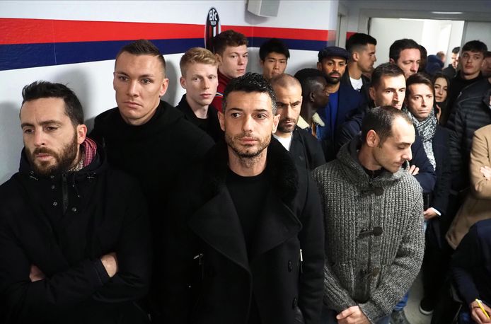 De spelersgroep van Bologna luistert naar zijn coach in het ziekenhuiszaaltje.