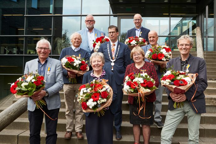 De kersvers gedecoreerden met elk een bloemetje verzameld op de trap aan de achterzijde van het gemeentehuis. voor een groepsfoto samen met burgemeester Joost van Oostrum.