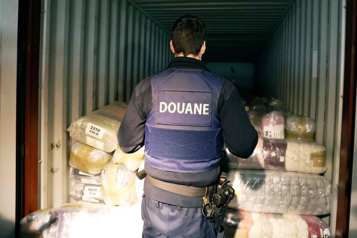 Des douaniers belges et un chien recherchent de la drogue dans un conteneur au port d'Anvers, le 7 janvier 2022.