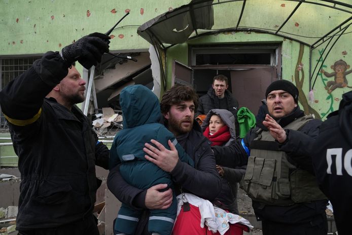 Een man haalt zijn kind weg uit het gebombardeerde ziekenhuis.