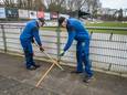 Kees Verduyn (l.) en Sjaak Snoek zijn bezig met het onkruid tussen de tegels te verwijderen.