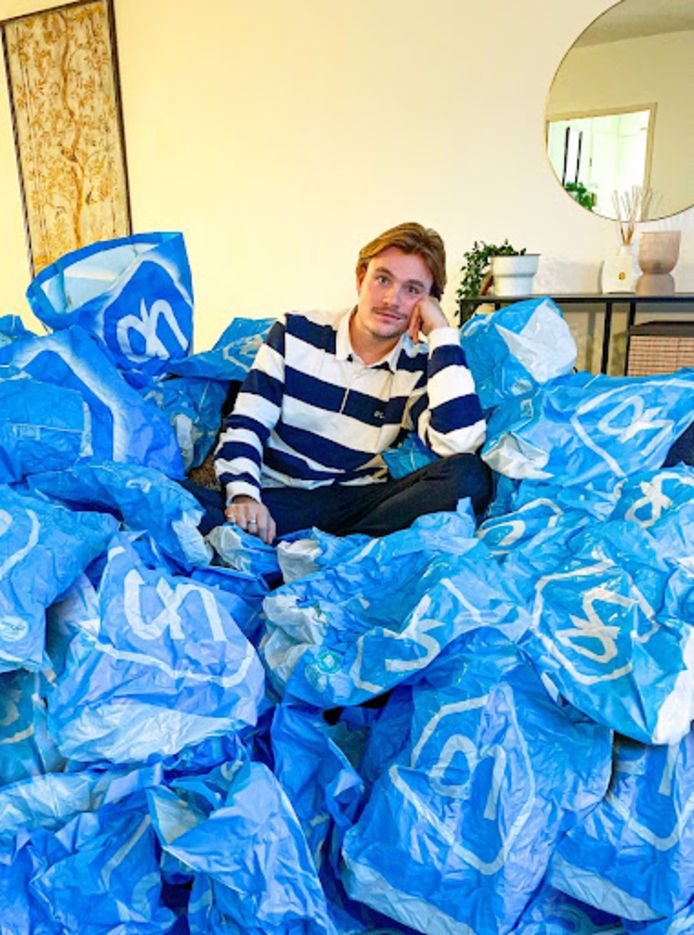 Nederlander Jasper van 't Wel tussen een berg plastic zakken van supermarktketen Albert Heijn.