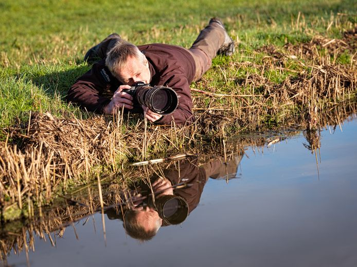 Natuurfotograaf Harry van ’t Veld in een hem kenmerkende pose in de polder Arkemheen.
