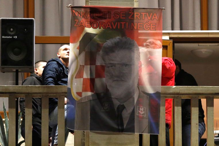 Bosnische Kroaten in het Bosnische Mostar hijsen een nationalistische vlag met een afbeeding van Praljak. Beeld AP