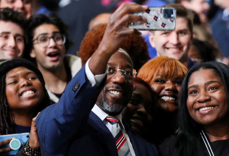 De Democratische kandidaat Raphael Warnock neemt tijdens een campagne-bijeenkomst voor de runoff-verkiezingen een selfie met zijn achterban. Beeld Reuters