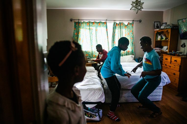Temetope uit Nigeria (46) danst met zoon Denver (11) in hun kamer. Dochter Danielle (8) kijkt toe terwijl zoon David (14) aan het computeren is. Beeld Aurélie Geurts