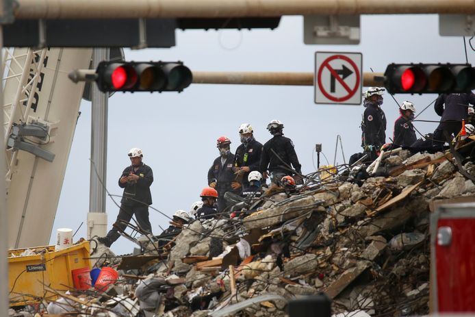 Reddingswerkers tussen het puin van het ingestorte gebouw.