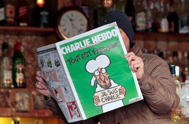 Een man leest het eerste Charlie Hebdonummer van na de aanslagen. Beeld REUTERS