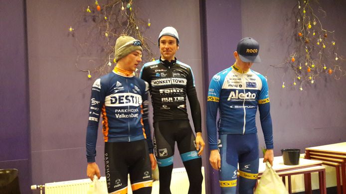 Vanwege de kou was het podium van de Omloop van de Houtse Linies naar binnen verplaatst. Ook daar baalde Abe Celi duidelijk nog altijd van het mislopen van de zege. De pas vader geworden Peter Schulting geniet ondertussen met volle teugen. Links de nummer drie Timo de Jong.