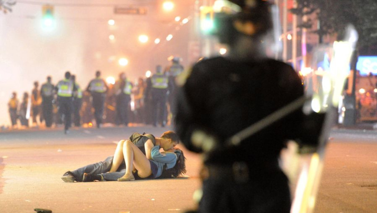 De onlusten in Vancouver, en een 'kussend' paar op de voorgrond. Foto: Richard Lam/Getty Beeld afp