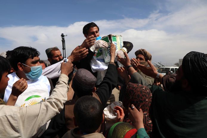 Een gezondheidsmedewerker deelt mondmaskers, handschoenen en desinfecteergel uit in Afghanistan.