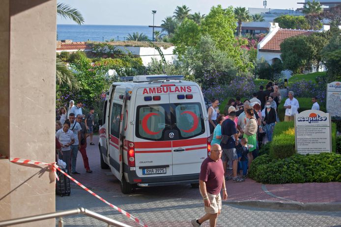 Een ambulance voor het getroffen hotel Acapulco in Kyrenia. Geschrokken toeristen wachten buiten.